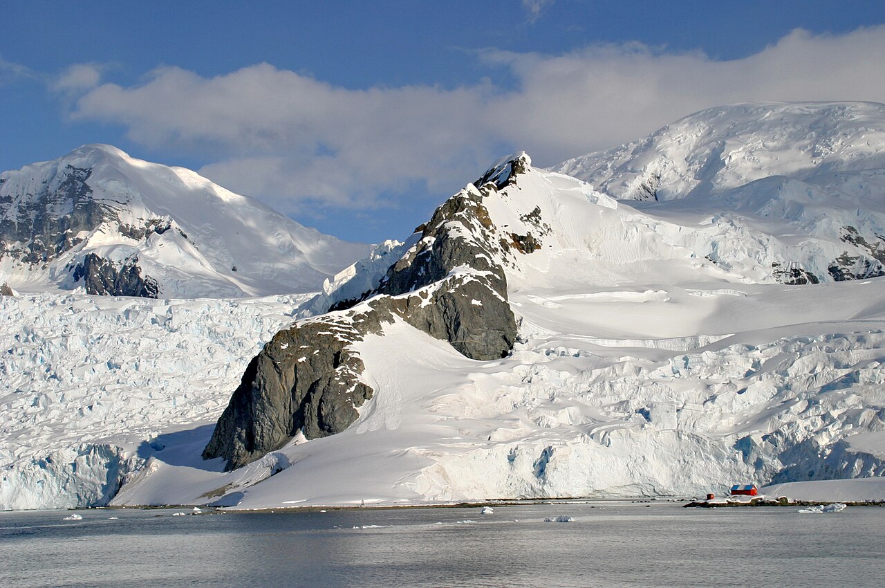 Snow-covered mountains and a glacier reflected in the calm water of Paradise Harbour, Antarctica